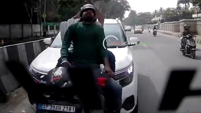 Car hits scooter from behind on a busy Bengaluru road, two people crash on road (Screen grab from viral video. ) Car hits scooter from behind on a busy Bengaluru road, two people crash on road (Screen grab from viral video. )