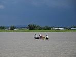 People wade through flood waters on a boat at Lehpati village of Morigaon district in India's northeastern state of Assam on July 3, 2024. (Photo by Biju BORO / AFP)(AFP)