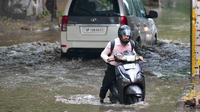 A commuter wades through a waterlogged road in Industrial Area, Chandigarh, following the rain on Tuesday morning. (Keshav Singh/HT)