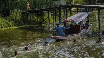 Children swim as a boat passes through Dal Lake during a hot summer day in Srinagar on Tuesday. (AP Photo) Children swim as a boat passes through Dal Lake during a hot summer day in Srinagar on Tuesday. (AP Photo)