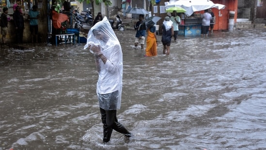 A man covers himself with a plastic sheet amid heavy rainfall in Surat. (File) (ANI)