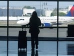 A traveller looks at a plane while standing inside an airport. 