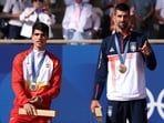 Gold medallist Novak Djokovic of Serbia gestures on the podium with silver medallist Carlos Alcaraz of Spain.