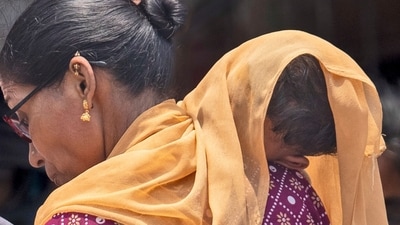 A woman covers her child with a scarf to save him from heat. (AP Photo/Rafiq Maqbool) (AP)