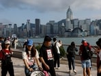 Tourists walk in front of the skyline of buildings at Tsim Sha Tsui, in Hong Kong. (REUTERS)