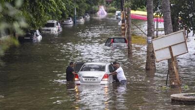 People try to move a car stuck in a waterlogged area after irrigation department released 31,515 cusecs of water from Khadakwasla Dam following heavy rains in catchment areas. (PTI)