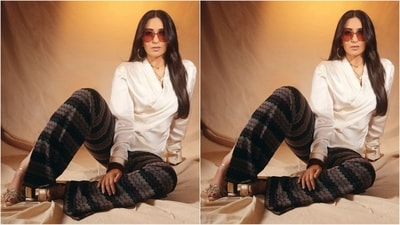 Karisma’s outfit, designed by Shantnu & Nikhil, features a white top with a V-neckline and full sleeves, complemented by tie-on detailing at the side. She paired it with striking black and grey trousers, creating a sophisticated and glamorous retro look. (Instagram/@therealkarismakapoor) Karisma’s outfit, designed by Shantnu & Nikhil, features a white top with a V-neckline and full sleeves, complemented by tie-on detailing at the side. She paired it with striking black and grey trousers, creating a sophisticated and glamorous retro look. (Instagram/@therealkarismakapoor)