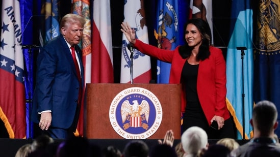 Former US Representative Tulsi Gabbard (R) waves after endorsing former US President and 2024 Republican presidential candidate Donald Trump (L) at the National Guard Association conference in Detroit, Michigan, on August 26, 2024. (Photo by JEFF KOWALSKY / AFP) (AFP)