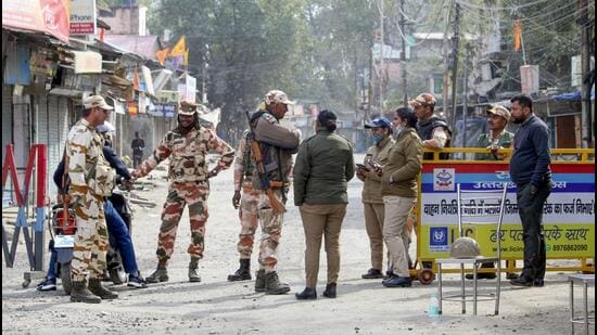 ITBP and Uttarakhand Police personnel stand guard on a road on February 12, 2024, during a curfew in Haldwani’s Banbhoolpura area following incidents of violence. (PTI File Photo)