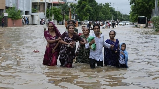 A family wades through a flooded road following heavy rainfall in Ahmedabad, Gujarat. (AP Photo)