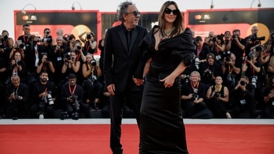 Monica Bellucci poses with director Tim Burton at the screening of Beetlejuice Beetlejuice at the Venice Film Festival. She wore a custom Vivian Westwood gown featuring statement sleeves, a plunging neckline, a corset bodice, and a fitted skirt. She styled the ensemble with an emerald and ruby necklace, sunglasses, and a mini clutch.&nbsp; (REUTERS)