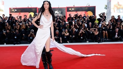 Mariacarla Boscono wore the first custom piece by Stefano Gallici for Ann Demeulemeester at the Venice Film Festival. She wore a white silk gown featuring a cowl neckline, a side thigh-high slit, and a stunning back with feather adornments. She wore the ensemble with black boots, feather headgear, and an emerald necklace. (Joel C Ryan/Invision/AP) Mariacarla Boscono wore the first custom piece by Stefano Gallici for Ann Demeulemeester at the Venice Film Festival. She wore a white silk gown featuring a cowl neckline, a side thigh-high slit, and a stunning back with feather adornments. She wore the ensemble with black boots, feather headgear, and an emerald necklace. (Joel C Ryan/Invision/AP)