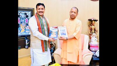 SSU vice chancellor Prof Bihari Lal Sharma presenting Durga Saptashati and Lok Mata Ganga to CM Yogi. (HT)