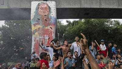 Protesters celebrate beside a defaced portrait of then Prime Minister Sheikh Hasina after news of her resignation, in Dhaka, Bangladesh, on August 5. (AP)