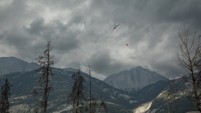 A helicopter buckets water onto smouldering fires outside Jasper, Alberta, Canada, on Friday July 26, 2024. AMBER BRACKEN/Pool via REUTERS (via REUTERS)