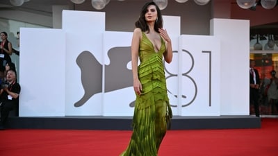 Emily Ratajkowski attended the Venice Film Festival in a vintage green gown from Gucci’s 2004 Fall/Winter Ready to Wear collection. The body-hugging dress features a plunging neckline, a playful skirt adorned with fringes, and sheer fabric adorned on the bust. She complemented her archival ensemble with delicate stacks of silver rings and a pair of dangling diamond earrings. (AFP) Emily Ratajkowski attended the Venice Film Festival in a vintage green gown from Gucci’s 2004 Fall/Winter Ready to Wear collection. The body-hugging dress features a plunging neckline, a playful skirt adorned with fringes, and sheer fabric adorned on the bust. She complemented her archival ensemble with delicate stacks of silver rings and a pair of dangling diamond earrings. (AFP)
