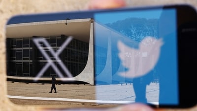 The logo of social media platform X is seen on a mobile phone next to a reflection of Brazil's Supreme Court in this illustration taken August 30, 2024, in Brasilia, Brazil. (Ueslei Marcelino/Reuters)