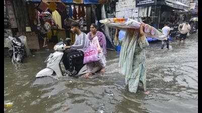 Commuters wade through a waterlogged street after rains in Jalandhar on Tuesday. (PTI)