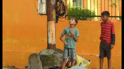 Kids stand next to exposed wires and cables hanging from an electric pole in Lucknow. (HT) Kids stand next to exposed wires and cables hanging from an electric pole in Lucknow. (HT)