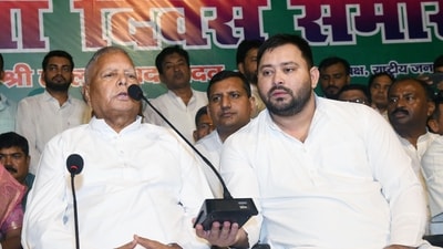 Leader of Opposition Tejashwi Yadav holds a mic while RJD Chief Lalu Prasad addresses party workers during 28th foundation of Rashtriya Janata Dal, at the party office in Patna, Bihar, India, Friday,05, 2024.(Photo by Santosh Kumar/ Hindustan Times)