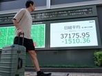 A man walks in front of an electronic quotation board displaying share prices on the Tokyo Stock Exchange in Tokyo. A man walks in front of an electronic quotation board displaying share prices on the Tokyo Stock Exchange in Tokyo.