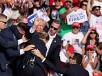 Republican presidential candidate and former U.S. President Donald Trump gestures with a bloodied face while he is assisted by U.S. Secret Service personnel after he was shot in the right ear during a campaign rally at the Butler Farm Show in Butler, Pennsylvania, U.S., July 13, 2024. 