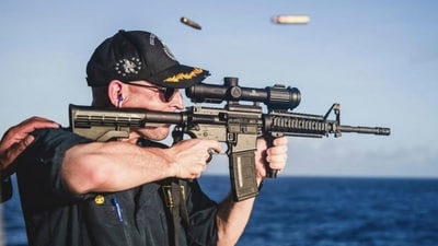 The photo shows US Navy warship commander Cameron Yaste firing a rifle with a backwards scope. (AP) The photo shows US Navy warship commander Cameron Yaste firing a rifle with a backwards scope. (AP)