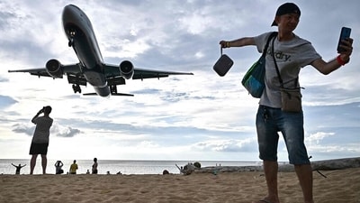 A tourist taking a selfie on Mai Khao Beach as an airplane lands at Phuket International Airport in the southern Thai island of Phuket. (AFP) A tourist taking a selfie on Mai Khao Beach as an airplane lands at Phuket International Airport in the southern Thai island of Phuket. (AFP)