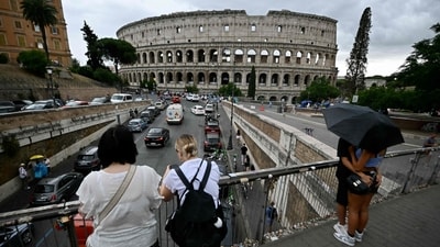 Tourists stand on a bridge near the Colosseum on July 3, 2024 in Rome. (Photo by Filippo Monteforte/AFP) Tourists stand on a bridge near the Colosseum on July 3, 2024 in Rome. (Photo by Filippo Monteforte/AFP)