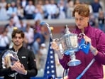 Jannik Sinner, of Italy, holds the championship trophy as Taylor Fritz, of the United States, looks on. Jannik Sinner, of Italy, holds the championship trophy as Taylor Fritz, of the United States, looks on.