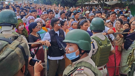 Protesters gather as security personnel block their way along a street during a curfew in Imphal on September 10, 2024. (AFP)