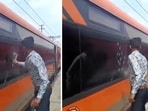 The image shows a man smashing the window pane of a Vande Bharat train with a hammer. 