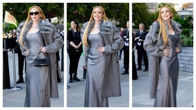 Lindsay Lohan wore a grey satin dress with a luxurious overcoat, which had a faux fur collar. She accessorised with a small black bag, a pendant, and sunglasses. Her ensemble radiated a vintage, old Hollywood charm. Lindsay Lohan wore a grey satin dress with a luxurious overcoat, which had a faux fur collar. She accessorised with a small black bag, a pendant, and sunglasses. Her ensemble radiated a vintage, old Hollywood charm.