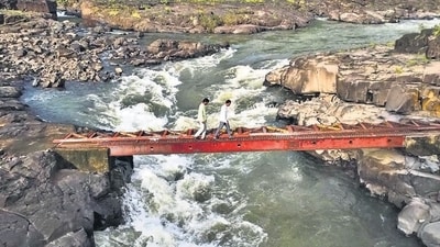 Villagers and schoolgoing children would use a dilapidated bridge to cross the Vaitarna river and reach Dapora village, five km away. Three years ago, the wooden plank they were using was replaced by a temporary iron bridge, now in bad condition. (Raju Shinde/HT Photo) Villagers and schoolgoing children would use a dilapidated bridge to cross the Vaitarna river and reach Dapora village, five km away. Three years ago, the wooden plank they were using was replaced by a temporary iron bridge, now in bad condition. (Raju Shinde/HT Photo)