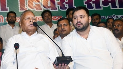 Leader of Opposition Tejashwi Yadav holds a mic while RJD Chief Lalu Prasad addresses party workers during 28th foundation of Rashtriya Janata Dal, at the party office in Patna. (Hindustan Times)