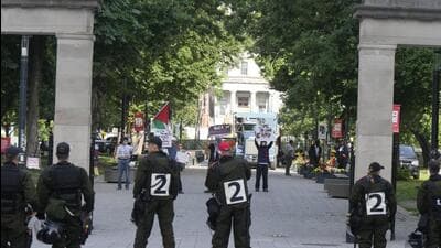 Police stand by as protesters holds up signs at McGill University in Montreal, on July 10. (AP) Police stand by as protesters holds up signs at McGill University in Montreal, on July 10. (AP)