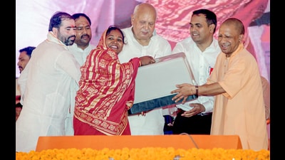 Uttar Pradesh Chief Minister Yogi Adityanath presents a sewing machine to a beneficiary during the foundation stone laying ceremony of development projects at Milkipur in Ayodhya on Thursday. (ANI)