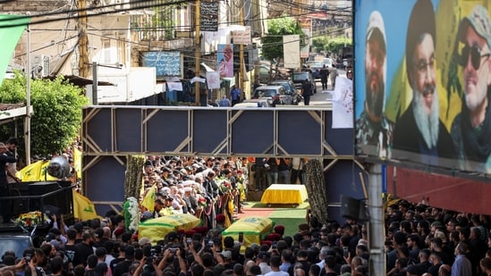Mourners gather near the coffins of Hezbollah members Fadel Abbas Bazzi and Ahmad Ali Hassan, after hand-held radios and pagers used by armed group Hezbollah detonated across Lebanon, during their funeral in Ghobeiry, Beirut southern suburbs, Lebanon September 19, 2024. REUTERS/Emilie Madi