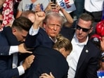 Republican candidate Donald Trump is seen with blood on his face surrounded by Secret Service agents as he is taken off the stage at a campaign event at Butler Farm Show Inc. in Butler, Pennsylvania, July 13, 2024. Donald Trump was hit in the ear in an apparent assassination attempt by a gunman at a campaign rally on Saturday, in a chaotic and shocking incident that will fuel fears of instability ahead of the 2024 US presidential election. (Photo by Rebecca DROKE / AFP)