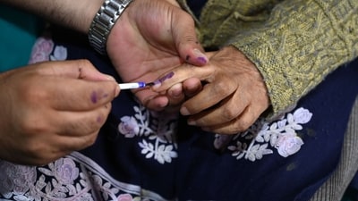 Kashmir, India - September. 21, 2024: An election officer applies indelible ink mark on the finger of Bibi, 87, before casting her vote from home, as the Election Commission of India (ECI) initiated a home voting facility for the elderly in the ongoing Jammu and Kashmir  Assembly elections in Srinagar,on September 21,2024.(Photo By Waseem Andrabi /Hindustan Times)--
