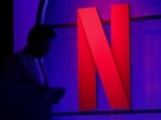 A man stands next to a logo of Netflix during an event in Mumbai, India.