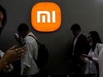 Visitors walk past a Xiaomi logo at the Beijing International Automotive Exhibition.
