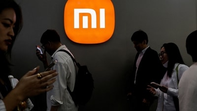 Visitors walk past a Xiaomi logo at the Beijing International Automotive Exhibition. (Reuters)