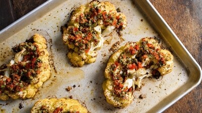 This image released by Milk Street shows a recipe for cauliflower steaks with pickled peppers, capers and parmesan. (Milk Street via AP) This image released by Milk Street shows a recipe for cauliflower steaks with pickled peppers, capers and parmesan. (Milk Street via AP)