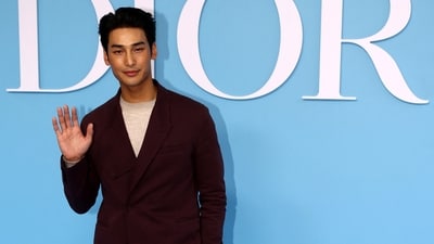 Nattawin Wattanagitiphat, aka Apo, poses during a photocall before the Dior Spring/Summer 2025 show. He wore a round-neck grey jumper styled with beige pants and a wine-red notch-lapel blazer.&nbsp; (REUTERS)