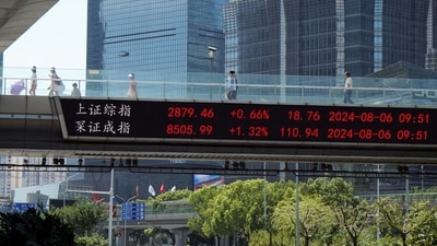 People walk on an overpass with a display of stock information in front of buildings in the Lujiazui financial district in Shanghai, China. (Reuters)