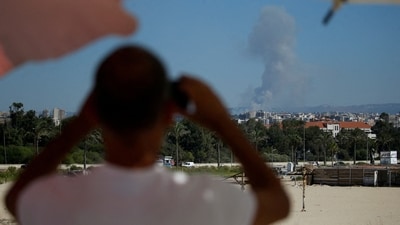 A man watches as smoke billows over southern Lebanon following an Israeli strike, amid ongoing cross-border hostilities between Hezbollah and Israeli forces. (REUTERS)
