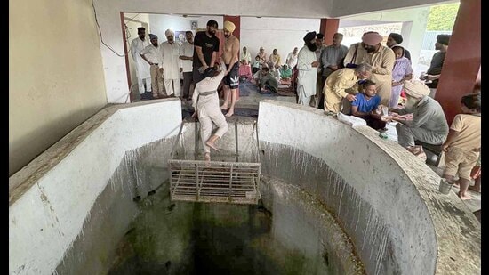 Healer along with his assistant lowering a patient with hernia problem in the magic well as a ritual to cure the ailment in village Jandiali in Ludhiana on Tuesday. (Gurpreet Singh/Hindustan Times)
