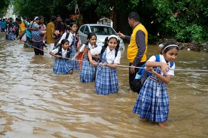 Students hold on to a rope as they cross a street flooded after heavy rains. (AP) Students hold on to a rope as they cross a street flooded after heavy rains. (AP)