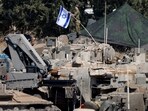An Israeli member of the military adjusts an Israeli flag as armoured vehicles are arranged in formation, amid cross-border hostilities between Hezbollah and Israel, in northern Israel, September 30, 2024. REUTERS/Jim Urquhart